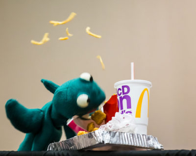 Puppet demolishing a fast food meal with fries flying