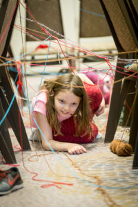 Child crawling through a yarn laser maze