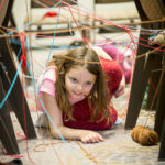 Child crawling through a yarn laser maze
